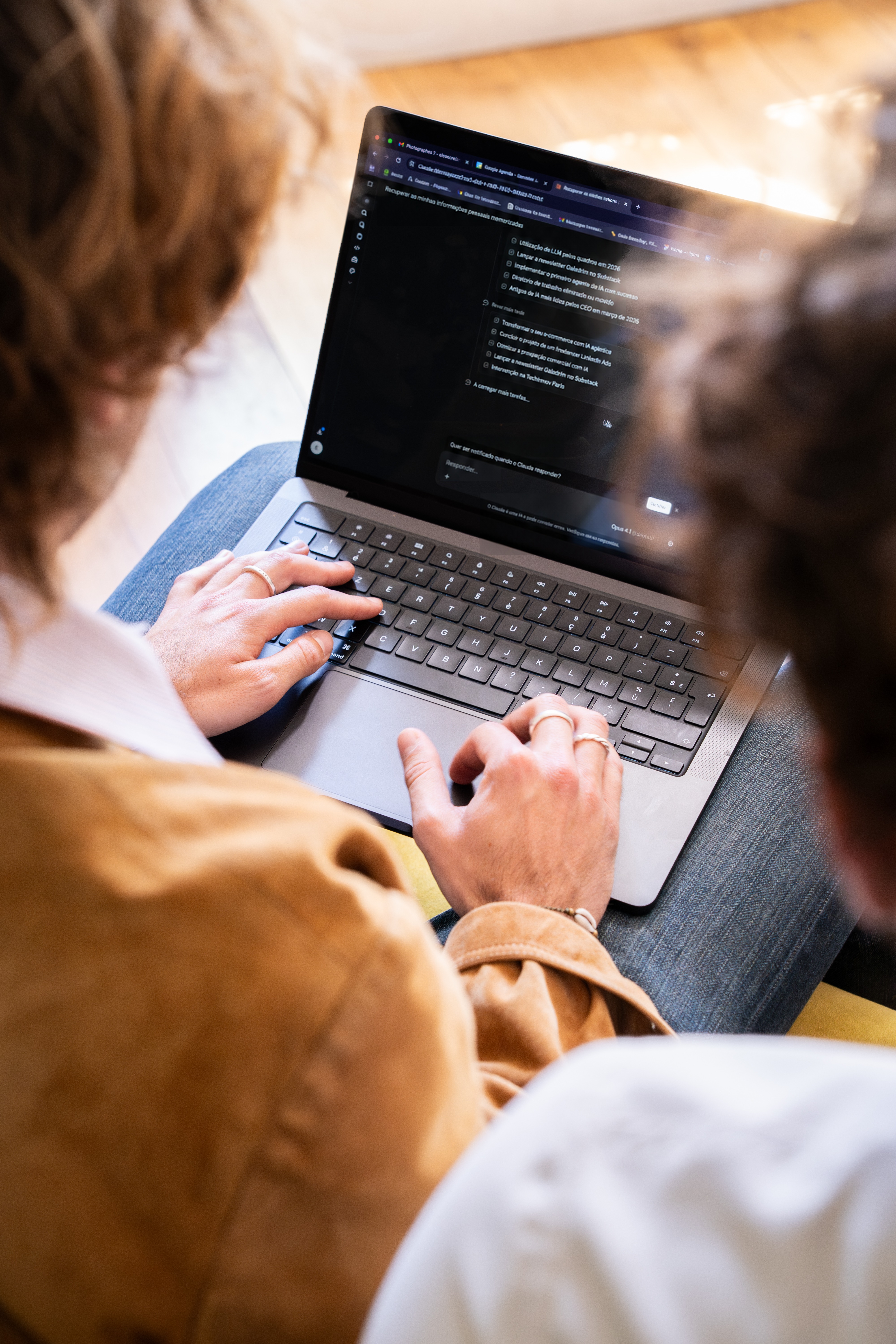 Duas pessoas de costas olhando um notebook que exibe uma interface de conversa com IA
