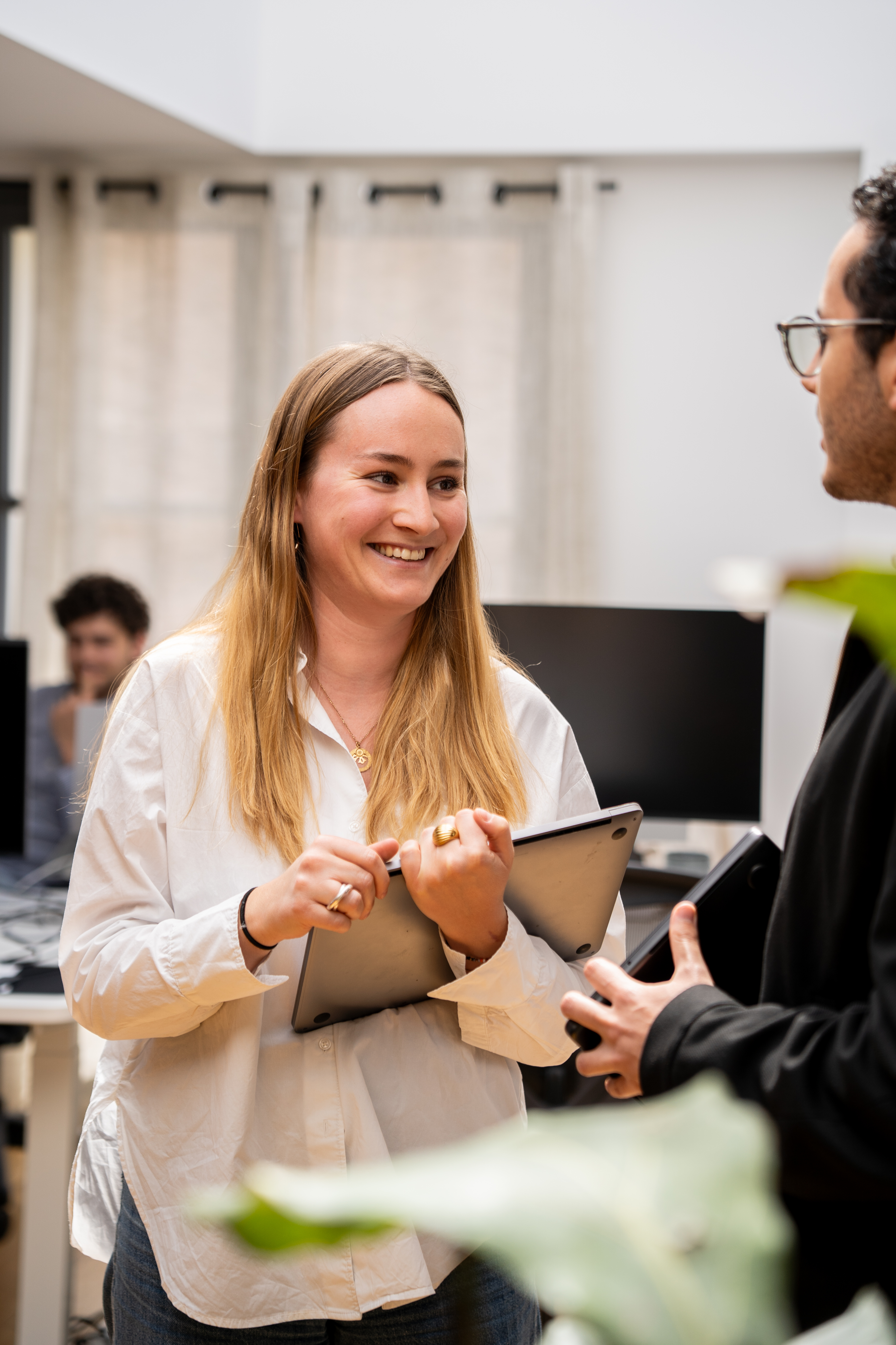 A Galadrimer shows a screen to a colleague in the open-plan office