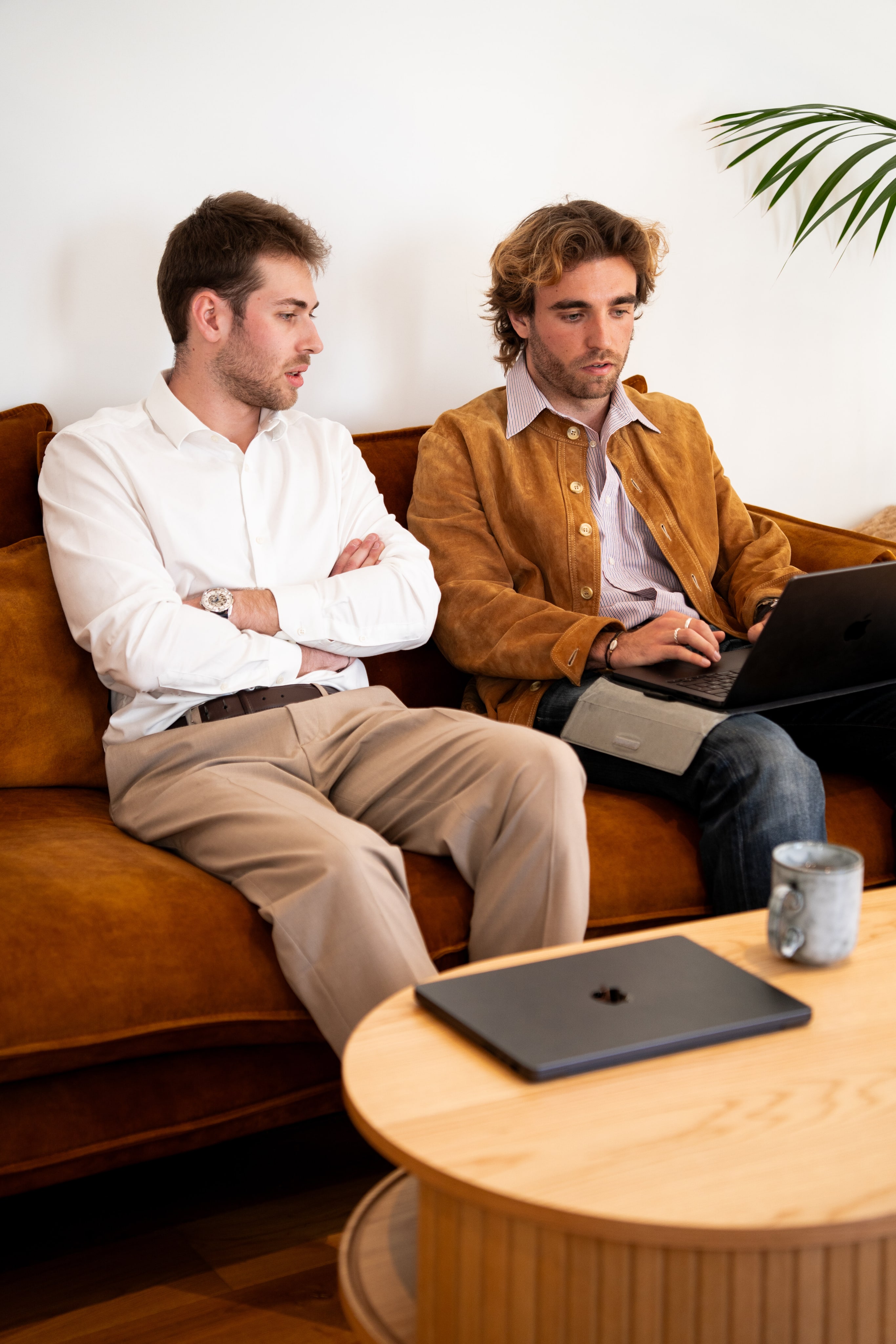 Deux Galadrimeurs assis sur un canapé, l'un avec un ordinateur portable sur les genoux, en pleine discussion.