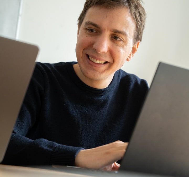 Galadrimeur souriant en visioconférence devant deux ordinateurs portables