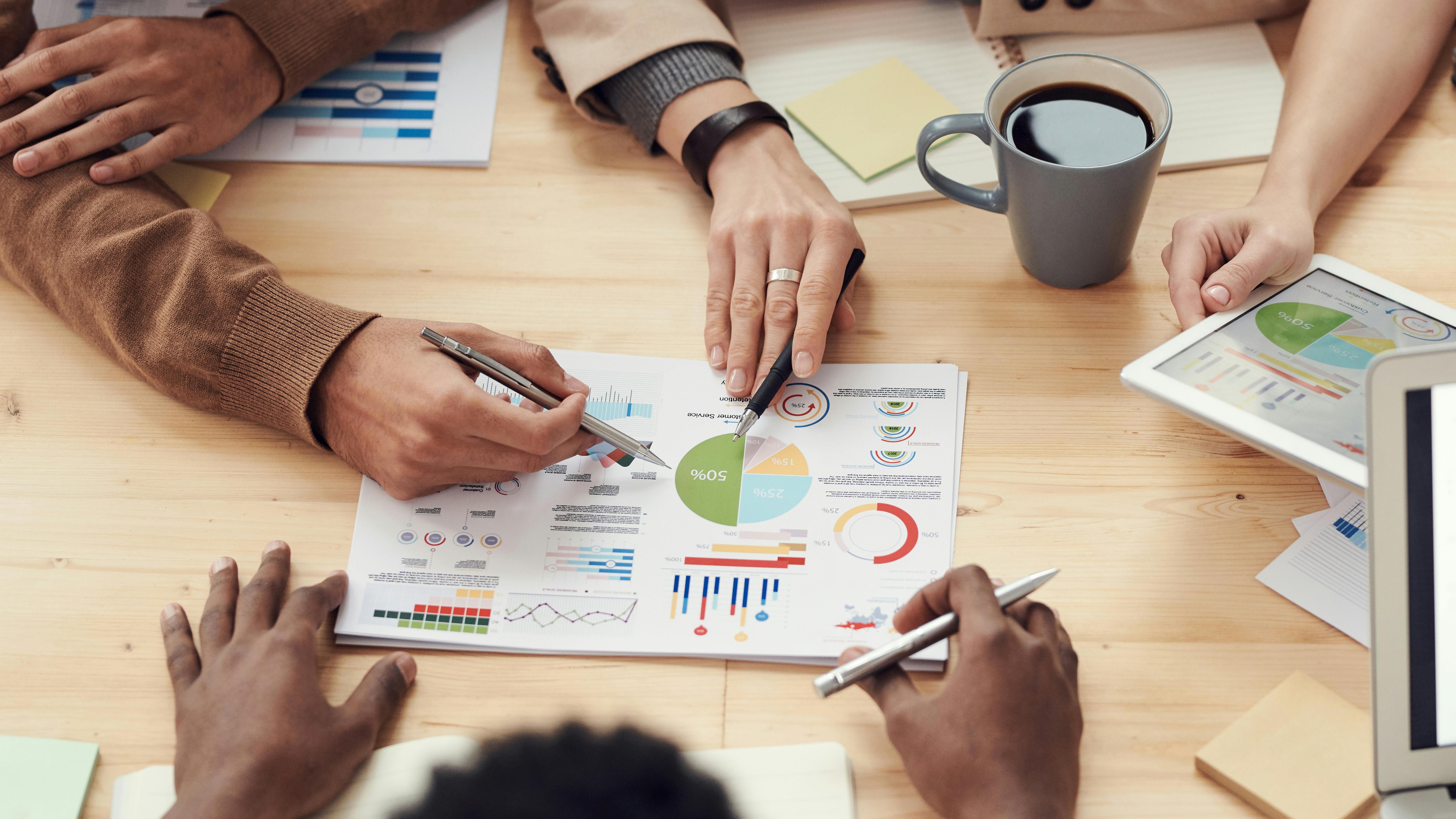 Plusieurs personnes analysent des graphiques autour d'une table en bois